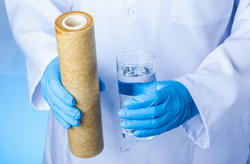 A glass of drink water and an used filter cartridge. Result of water treatment technology.