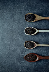 Assorted black food ingredients on wooden spoons ( beluga lentils, wild rice, sesame, chia). flat lay. copy space