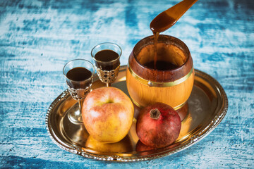 Pouring honey on apple and pomegranate with honey symbols of Jewish New Year - Rosh Hashanah.