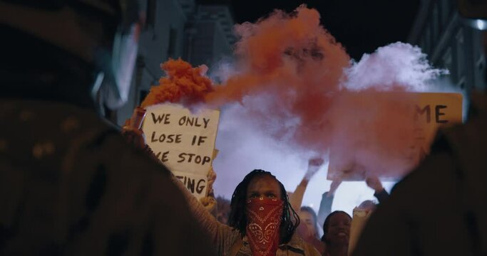 Protestors demonstrating with smoke grenades in front of the security force at night. Anti-government protest by the social activist group.
