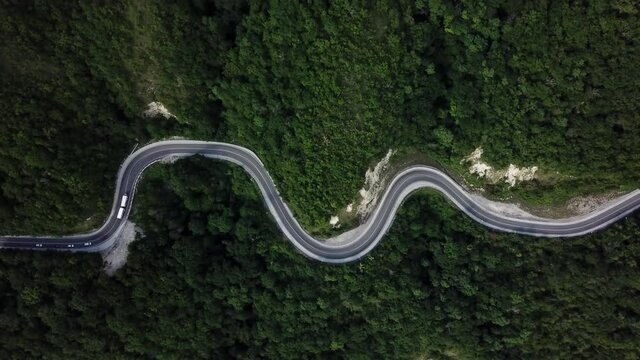 Mountain winding zig zag road. Top aerial view: cars driving on road from above.