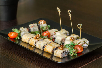Skewer rolls with walnuts and tomatoes on a table in a restaurant