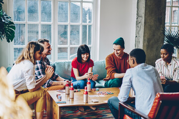 Cheerful woman using smartphone during poker game with friends - obrazy, fototapety, plakaty