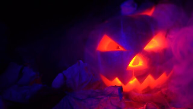 Halloween, pumpkins on the leaves. red luminous lights inside them, smoke from the side, smoke from a car.