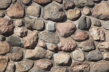 Old stable stone wall with rows of nature masonry stones. Brickwork with individual craft bricks pattern. Strong manual work construction build has stability. Nice creativity vintage pattern