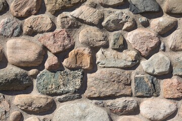 Old stable stone wall with rows of nature masonry stones. Brickwork with individual craft bricks pattern. Strong manual work construction build has stability. Nice creativity vintage pattern