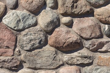 Old stable stone wall with rows of nature masonry stones. Brickwork with individual craft bricks pattern. Strong manual work construction build has stability. Nice creativity vintage pattern