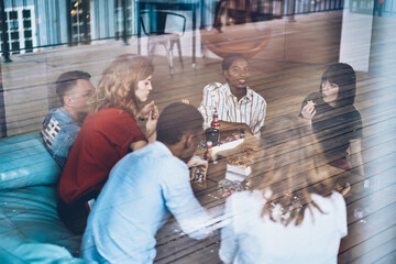 Smiling black woman looking at camera while eating pizza with friends