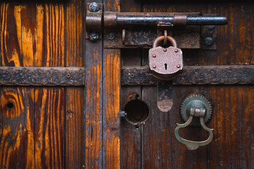 High contrast antique wooden door and antique metal bolt lock with large key padlock