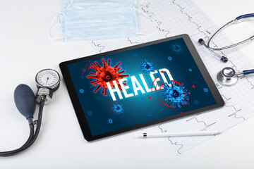 Tablet pc and doctor tools on white surface with HEALED inscription, pandemic concept