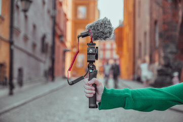 Hand holding a camera with microphone, vlogger with camera recording a video blog, content creation...