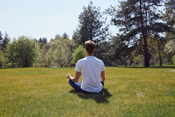Peaceful young man doing meditation in nature