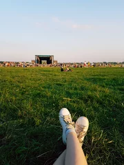 Foto op Canvas Relaxing at open air music festival in Ukraine. Traditional celebration with famous music groups performing on stage. Listening to live music looking at crowd when laying down on the green grass lawn. © Juliet Dreamhunter
