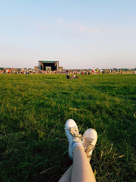 Relaxing At Open Air Music Festival In Ukraine. Traditional Celebration With Famous Music Groups Performing On Stage. Listening To Live Music Looking At Crowd When Laying Down On The Green Grass Lawn.