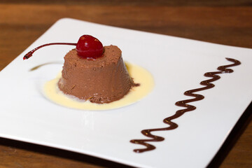 dessert of black chocolate mousse with white chocolate sauce and cherry