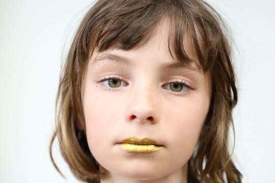 Portrait of a child with golden lips and a weary look
