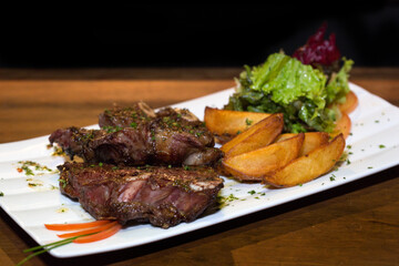roasted meat with rustic potatoes on wooden table