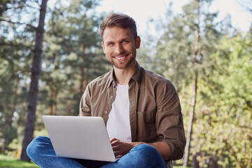 Pleased young male using portable computer outdoors