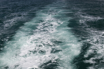 Trail on water surface behind of fast moving ship