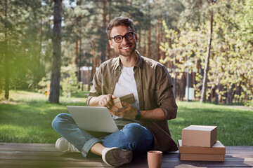 Pleased intelligent man holding a postal package