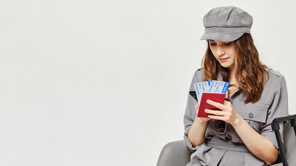 Girl is typing on smartphone and holding plane tickets with passport.