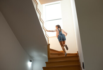 Cute little girl climbing the stairs at home