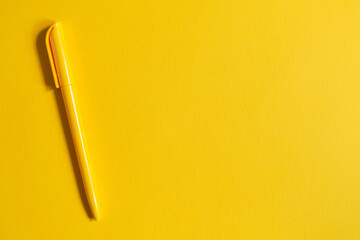 Yellow pen on yellow background with top view and copy space.