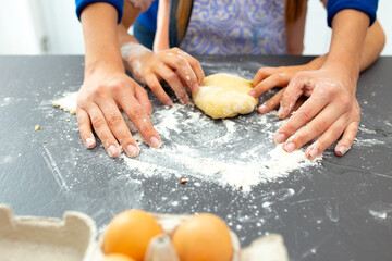 Daughter helping mother to prepare dough for cookies