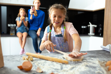 Cute female child preparing dough for cookies in kitchen