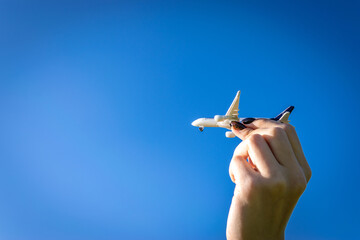 Flight plane white toy on sun light background. Bright airplane in woman hand travel in sunlight sky. Aircraft fly in air concept.