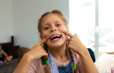 Cheerful little girl pointing at her milk mustache
