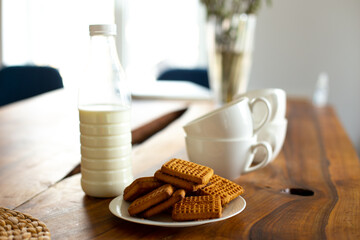 Wooden table with plate of cookies and milk