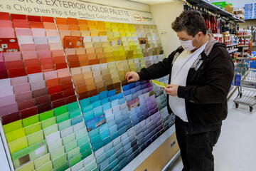 Man chooses paint in the hardware store with coronavirus masks shopping on walmart local store