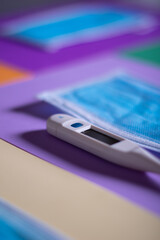thermometer and masks on coloured background