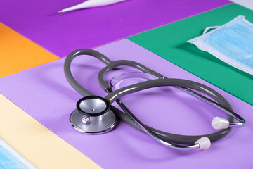 Stethoscope, face masks and hydroalcohol and face masks in colored background