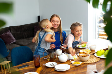 Obraz na płótnie Canvas Loving mother enjoying breakfast with adorable kids
