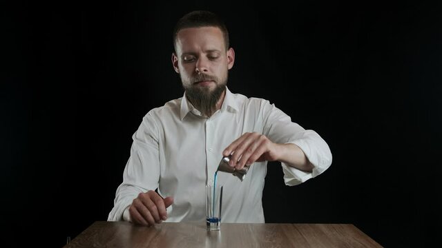 Bartender pouring blue curacao liquor into glass from jigger