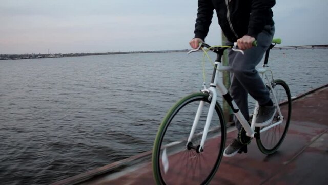 Young active man rides sport bicycle, evening river landscape, healthy lifestyle