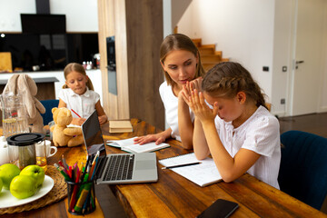 Fototapeta premium Loving mother helping cute daughter to do homework