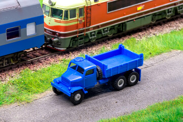 Blue scale truck on model train railroad layout road near train