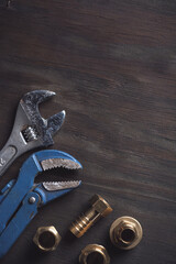 Plumbing. Different wrenches, pipe, tube, fittings and connectors on a wooden rustic table.
