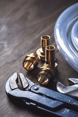 Plumbing. Different wrenches, pipe, tube, fittings and connectors on a wooden rustic table.