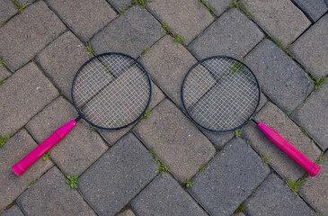 Isolated small badminton tennis rackets laying on grass ground. Rackets on paver patio floor. - 357960468