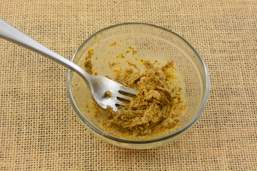Homemade chimichurri butter sauce with fork in glass mixing bowl for putting on meat
