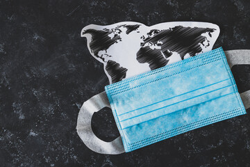 new normal after covid-19, world map with coronavirus mask on top of business desk