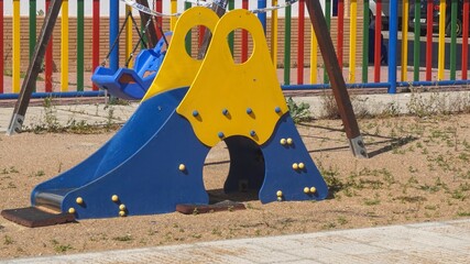 Yellow-blue slider in an outdoor kids playground on a sunny day