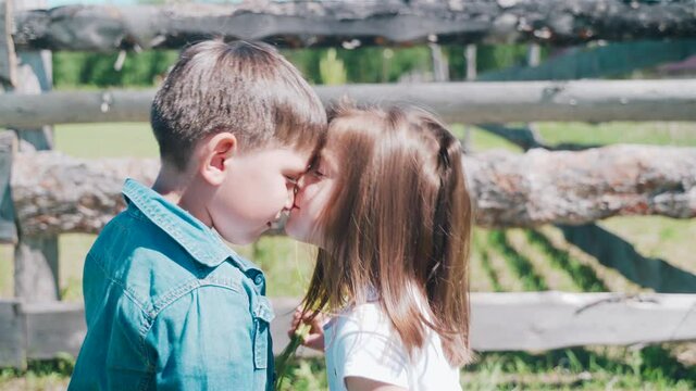 Boy present the flowers to the girl. Girl is kissing the boy. Brother and sister have fun. Twins spend time together. Summer holiday.