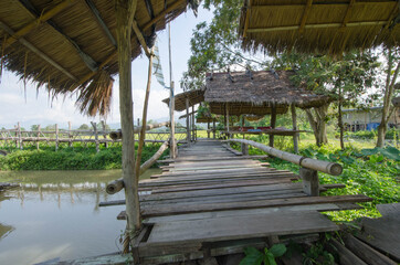 Fototapeta na wymiar Long wooden bridge to rest grass pavilion
