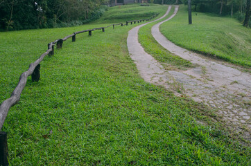 Two long road and wooden fence on green hill