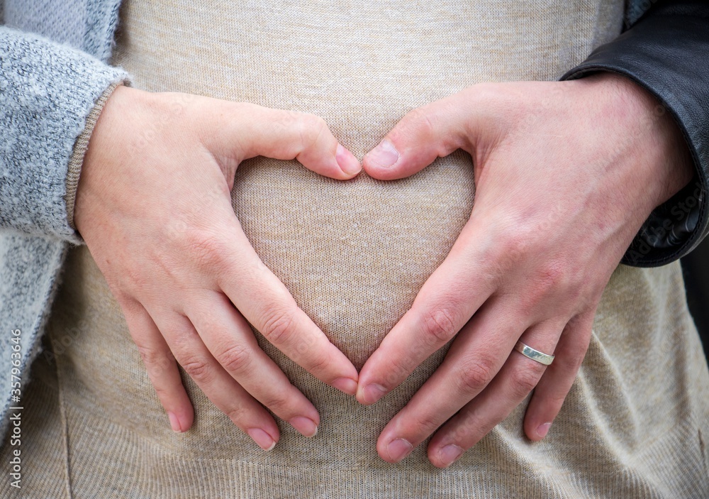 Wall mural Parents forming a heart on the belly of a pregnant female - parenthood concept